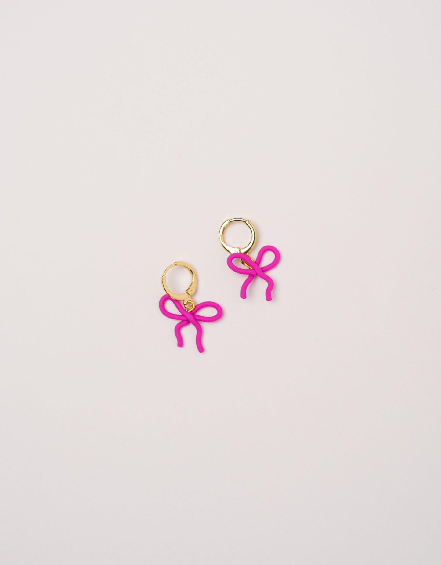Wavy Bow earrings by Little APÖ, handmade polymer clay earrings in a small wavy ribbon shape, unicolor, lightweight, and designed for young girls.