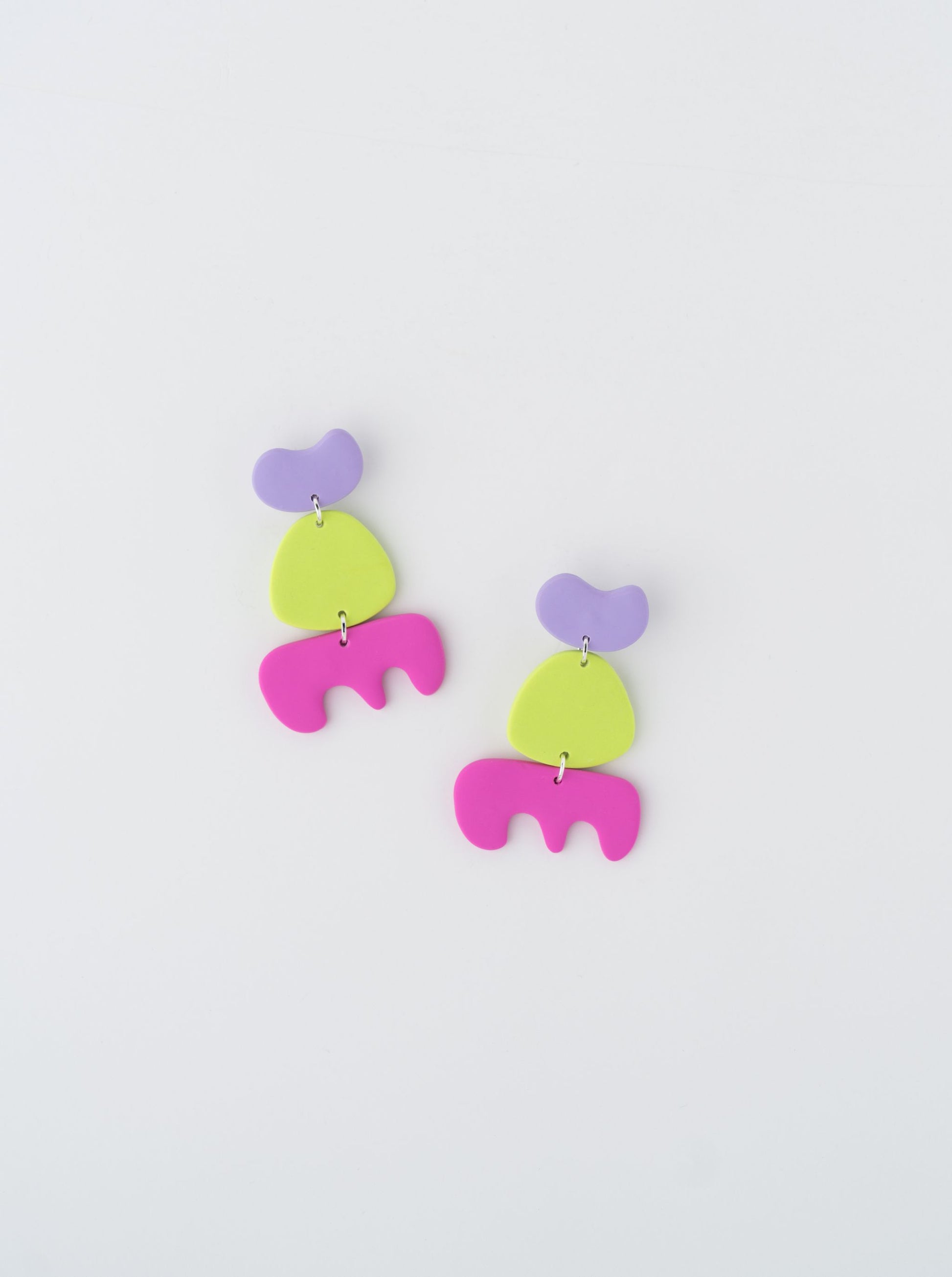 Walking earrings by APÖ, handmade polymer clay earrings featuring three abstract shapes in contrasting colors, medium-sized, lightweight, and expressive.